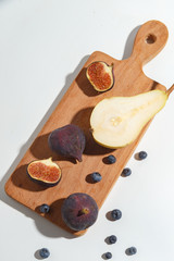 Figs, pear and blueberries on a cutting wooden board.