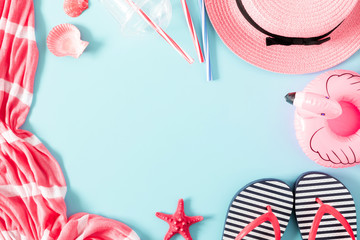 Summer beach composition. Beach pink accessories, straw hat, flip flop, starfish on blue background. Concept of summer vacations. Flat lay, top view, copy space