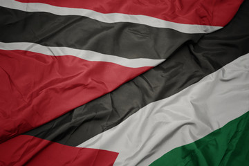 waving colorful flag of palestine and national flag of trinidad and tobago.