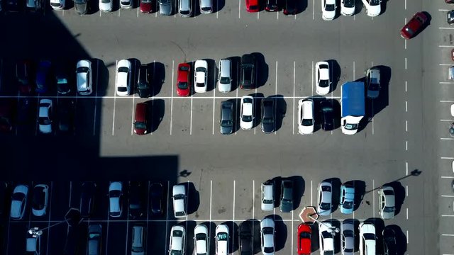 A view from above to the process of car parking. Heavy traffic in the parking lot. Searching for spaces in the busy car park. Parking advice. Cruising for parking in busy business center