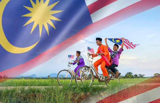 independence Day concept - Two happy young local boy riding old bicycle at paddy field holding a Malaysian flag