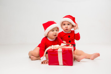  two toddlers in Santa Claus costumes with gift box on white isolate background