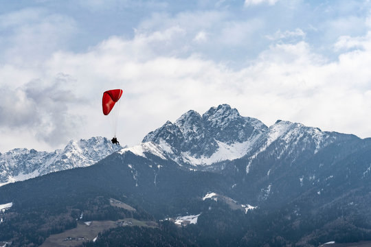 Two people flying with a Tandem and enjoying the freedom, high up in the sky with a few clouds and mountains covered in snow in the background
