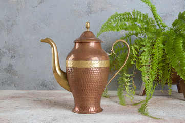 Antique copper coffee pot on concrete background.
