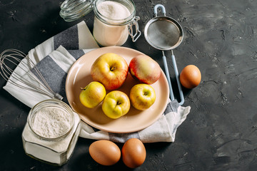 Autumn apple pie. Ingredients and cooking. Apples, eggs, flour, sugar. On a dark wooden background...