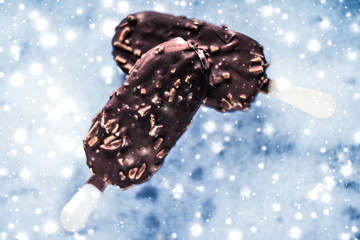 Chocolate almond ice cream on marble table with glowing snow, winter holiday food background