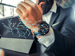 bearded adult rich businessman who has smart watch using his pro tablet and work remotely holographic intel web floating connects his smartphone and smartwatch and tablet