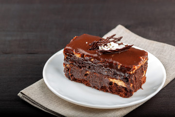 Dish with a slice of chocolate cake stands on a wooden table