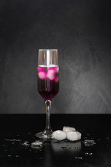 glass with ice on a black background. melting ice around splashing drops