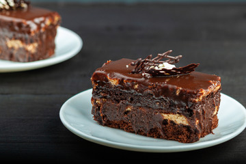 Dish with a slice of chocolate cake stands on a wooden table