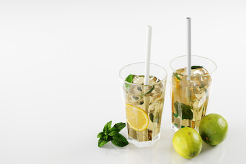 Lemonade, limes and mint leaves on white background.  refreshing drinks concept