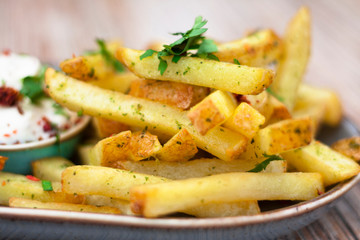 French fries with mayonnaise dressing and parsley on a plate outside. Close up.