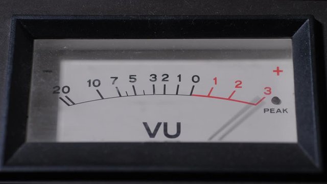 Closeup of standard volume indicator displaying representation of signal level in audio equipment working in sound record studio. Classic analog VU meter with display, scale and moving needle