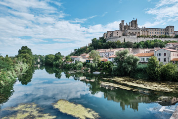 Fototapeta na wymiar Old medieval town rounded by green forest and reflected in the water. Béziers, France