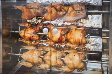 A few whole chickens are fried on an electric skewer