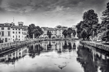 Landscape view of the river Sile flowing through the city. Buildings around. Black and White. Treviso, Veneto, Italy.