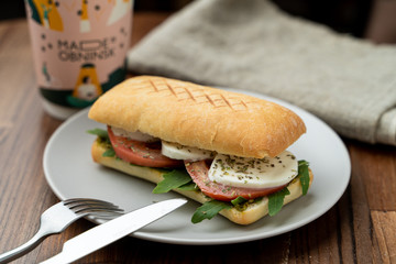 Grilled caprese ciabatta with tomatoes, pasta sauce and mozzarella, served with a cup of coffee
