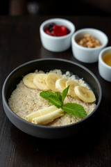 Close up of whole grain porridge with different toppings, served on dark table as a healthy substantial breakfast