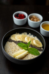Close up of whole grain porridge with different toppings, served on dark table as a healthy substantial breakfast