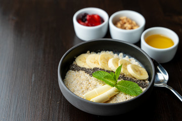 Close up of whole grain porridge with different toppings, served on dark table as a healthy substantial breakfast