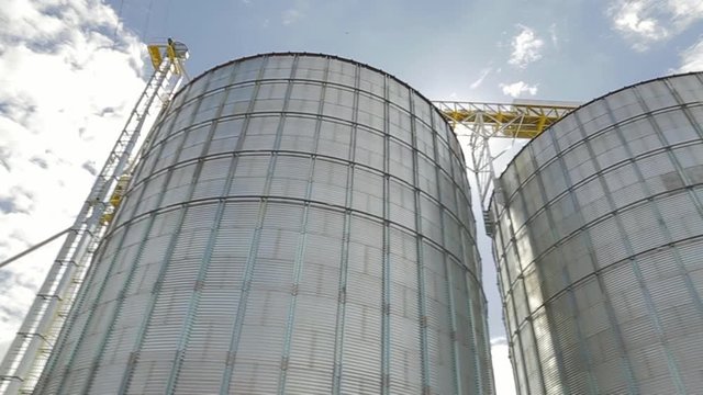 Modern metallic silo for grain storage with blue sky background.