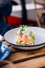 Avocado toast with smoked salmon and poached egg at hipster coffee shop