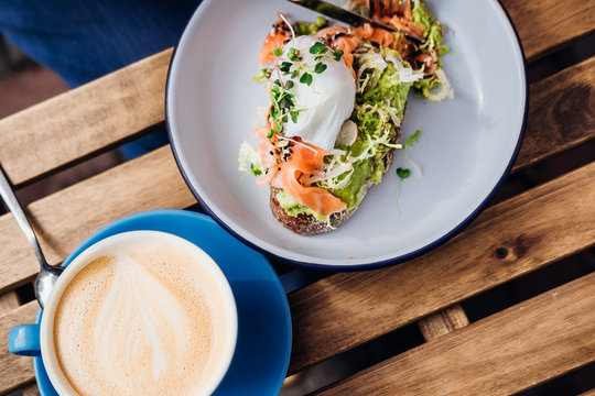 Avocado toast with smoked salmon and poached egg at hipster coffee shop