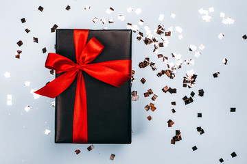 Black gift box with red ribbon on blue background. Black friday sale concept.