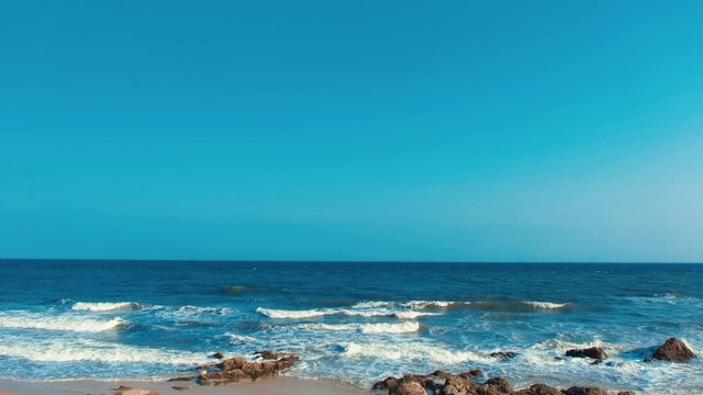 Stock 4k: Beautiful beach background with sea, waves, horizon and blue sky. Royalty high-quality free stock video footage of nobody on the beach. The sea is a great place to visit in the summer