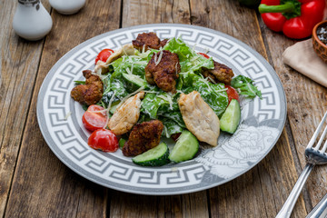Salad with chicken liver on old wooden table