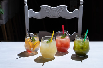 Side view of various of refreshing summer lemonades: classic lemon soda, strawberry lemonade,...