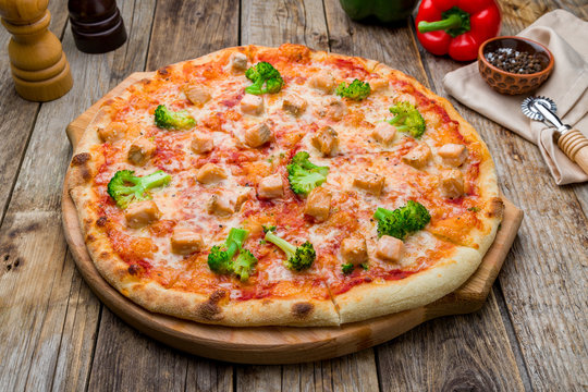 Pizza with salmon and broccoli on old wooden table