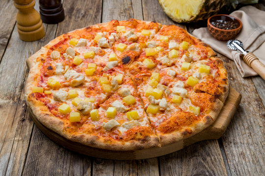 pizza Hawaiian with pineapple and chicken on old wooden table