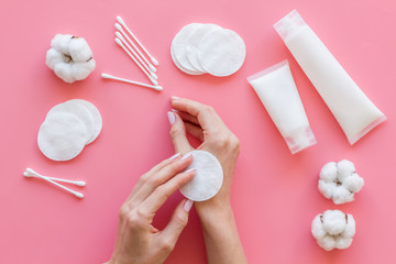 Cotton pads in hands, swabs and cream for blog design on pink background top view