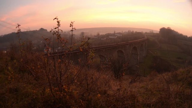 The old railroad bridge, built in the time of Austro-Hungarian Empire in Western Ukraine in Ternopil region. Sunset on the viaduct beauty shot from the slider.