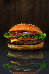 Fresh delicious Burger on a wooden background on a glossy table with reflection