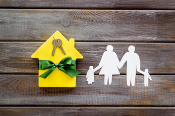 Apartment purchasing with house and family figure on wooden background top view