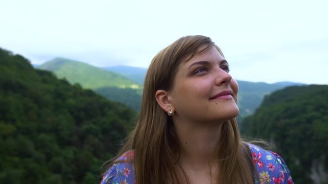 Young Woman smiles. Tourist Travel Vacation. Traveling mountains, freedom and active lifestyle concept. Young girl traveler at cityscape beautiful view background in Okatse canyon, Georgia. Slow mo