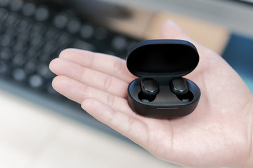 Black wireless bluetooth headphones on the hand