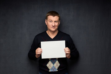 Portrait of pleased man holding white blank paper sheet