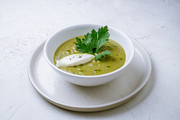 Cream of broccoli soup on white concrete table