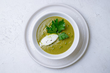 Cream of broccoli soup on white concrete table