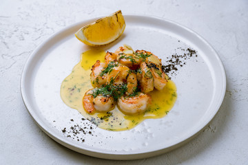 Tiger prawns on the grill with sause and greens on white concrete table