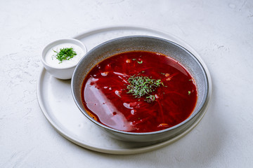 Borscht with sour cream on white concrete table