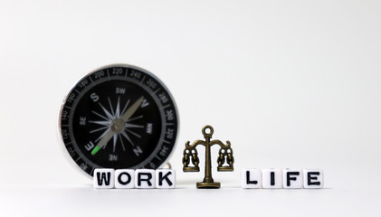 A miniature scale between WORK word and LIFE word on white cubes in front of the compass.