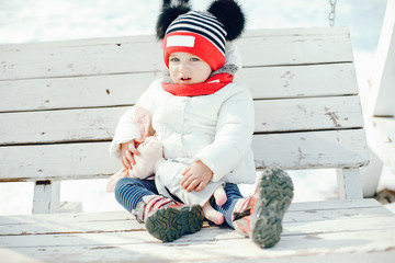 Little girl in a cute hat. Daughter in a winter park.