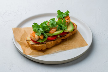 Bruschetta with prawns and avocado on white concrete table