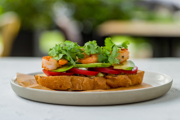 Bruschetta with prawns and avocado on white concrete table