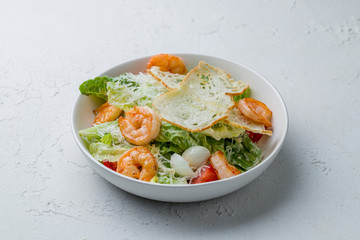 salad caesar with shrimps on white concrete table
