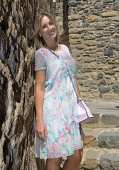 Blonde woman with brackets smiles while looks at the camera in a medieval village